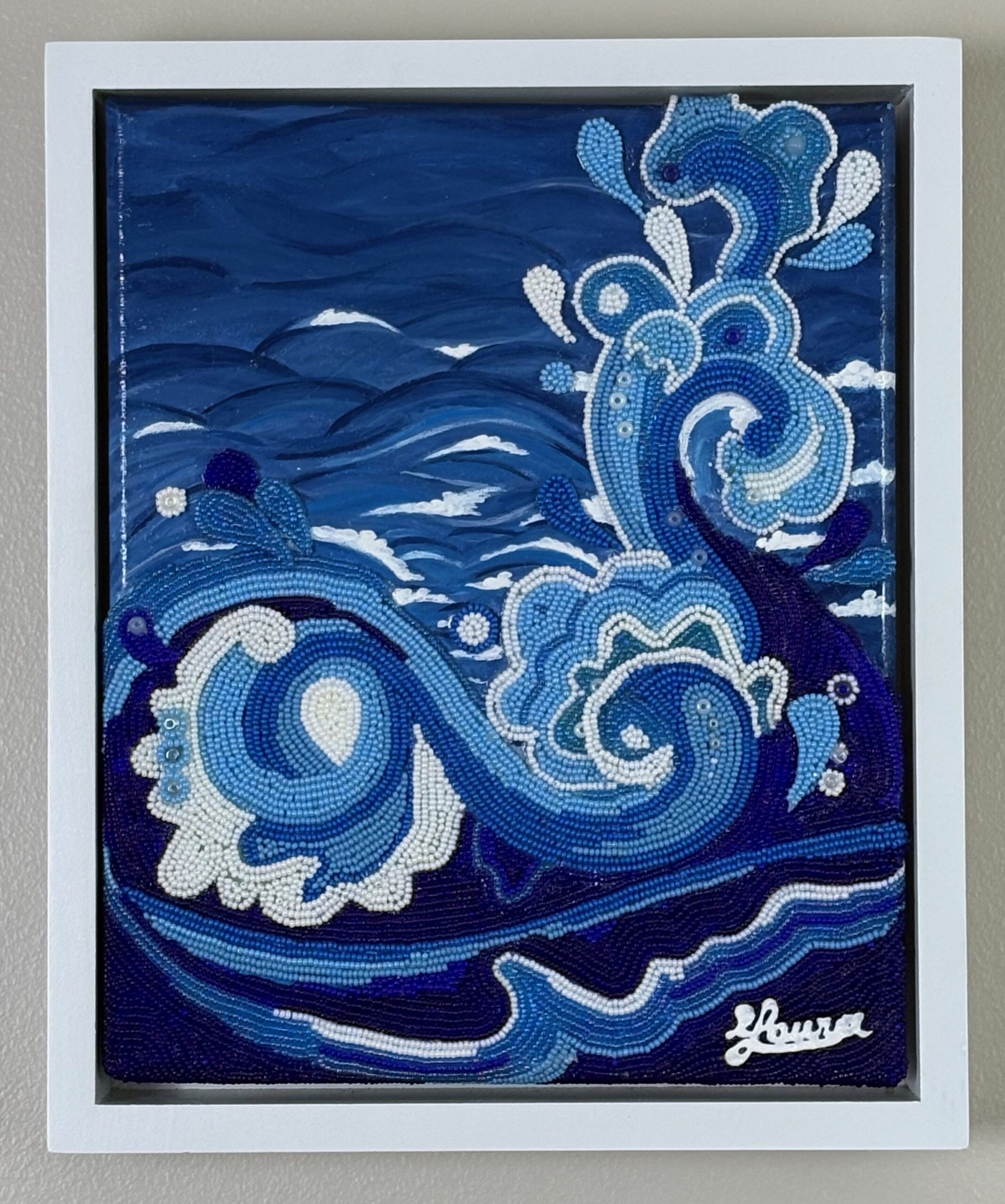 Blue and white beaded waves curl across a painted ocean background in Water, a small bead mosaic in a white frame.