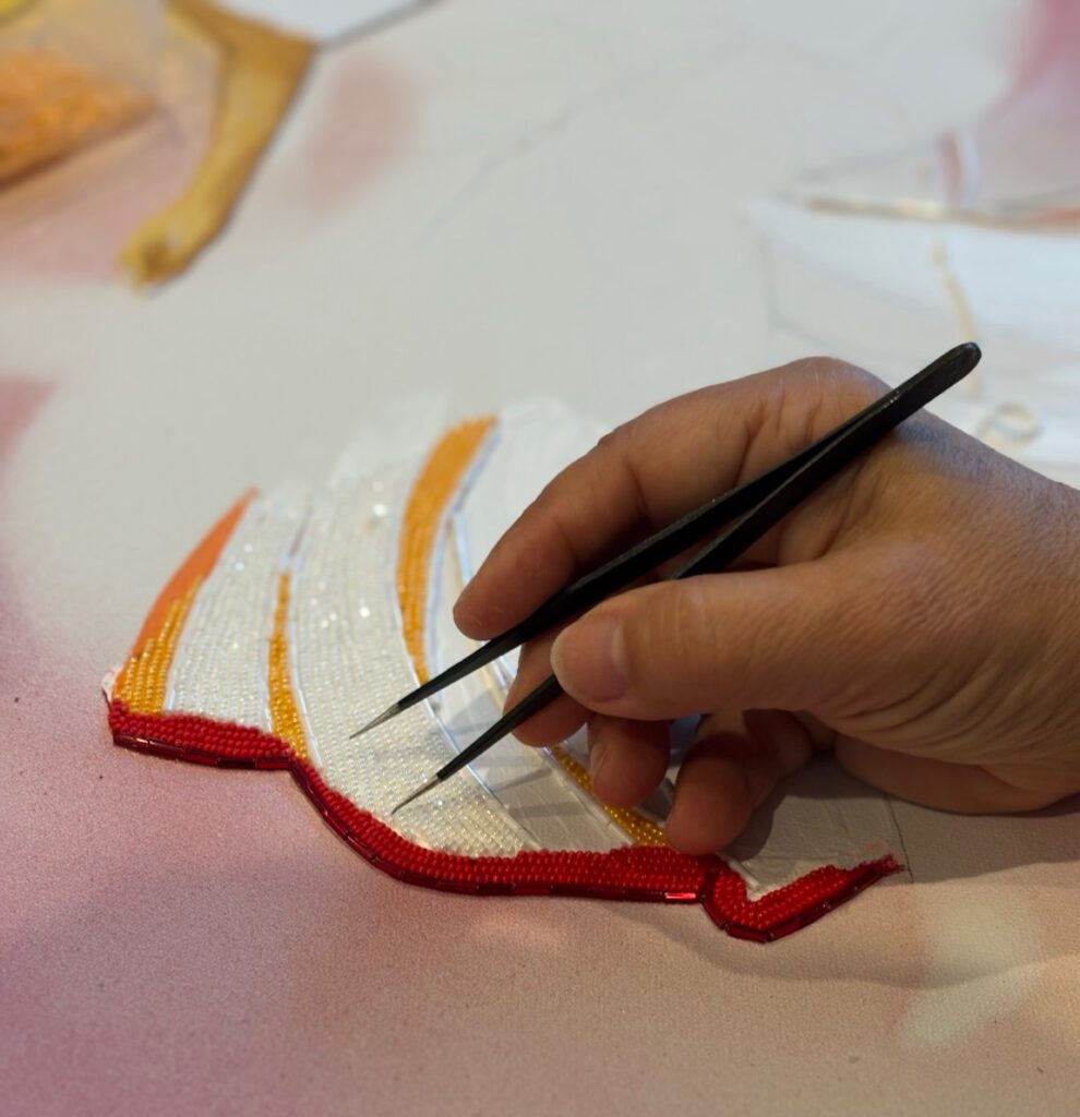 Maria Laura placing beads by hand with tweezers on a contemporary mixed media bead mosaic